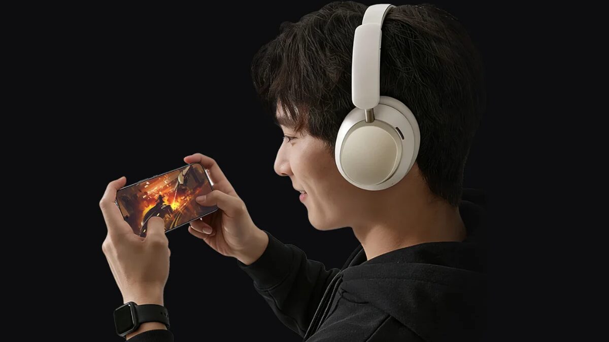 Молодой человек в наушниках Honor Choice Codeler Headphones 2 играет в мобильную игру