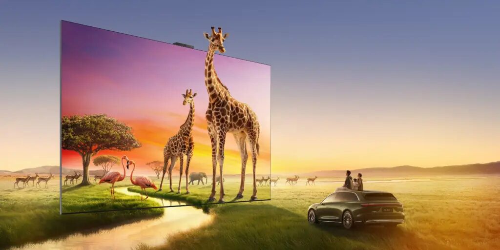Гости у автомобиля смотрят на телевизор Huawei Vision Smart Screen S7 Pro с изображением жирафов и зебр на заднем плане