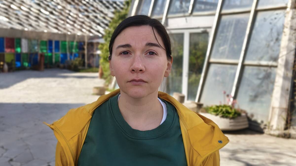 женщина в желтой куртке и зеленом свитере с текстом в парке