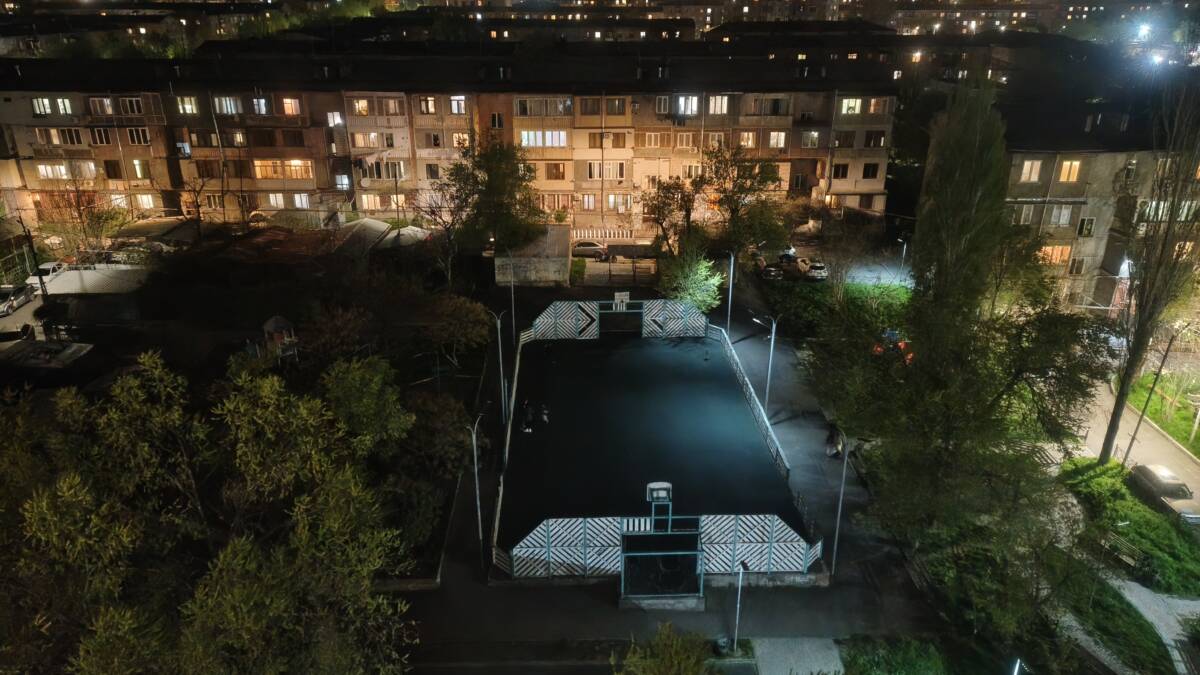 ночной городский пейзаж, здания с освещением, спортплощадка, деревья