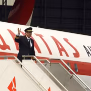 Пилот в пилотской форме на ступеньках самолёта Boeing 707 Траволты