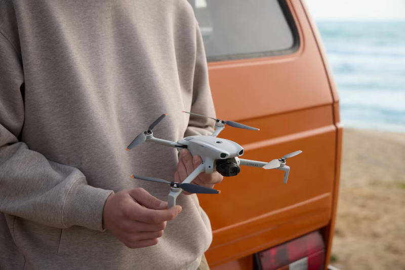 Человек держит DJI Lito 1 и Lito X1 у машины