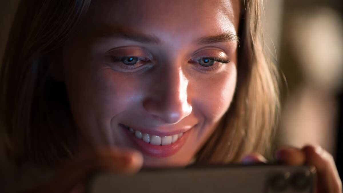 Женщина в ярком свете использует мобильный телефон клюевой мессенджер