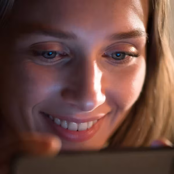 Женщина в ярком свете использует мобильный телефон клюевой мессенджер