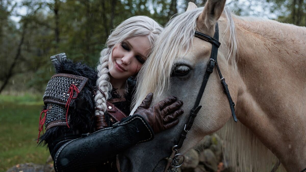 Девушка с белыми волосами в костюме Цири из Ведьмака и лошадь