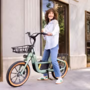 Женщина с кудрявыми волосами и белой рубашкой рядом с электровелосипедом Segway Muxi на улице