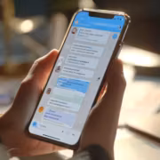 Человек держит iPhone, показывает Telegram чат на экране