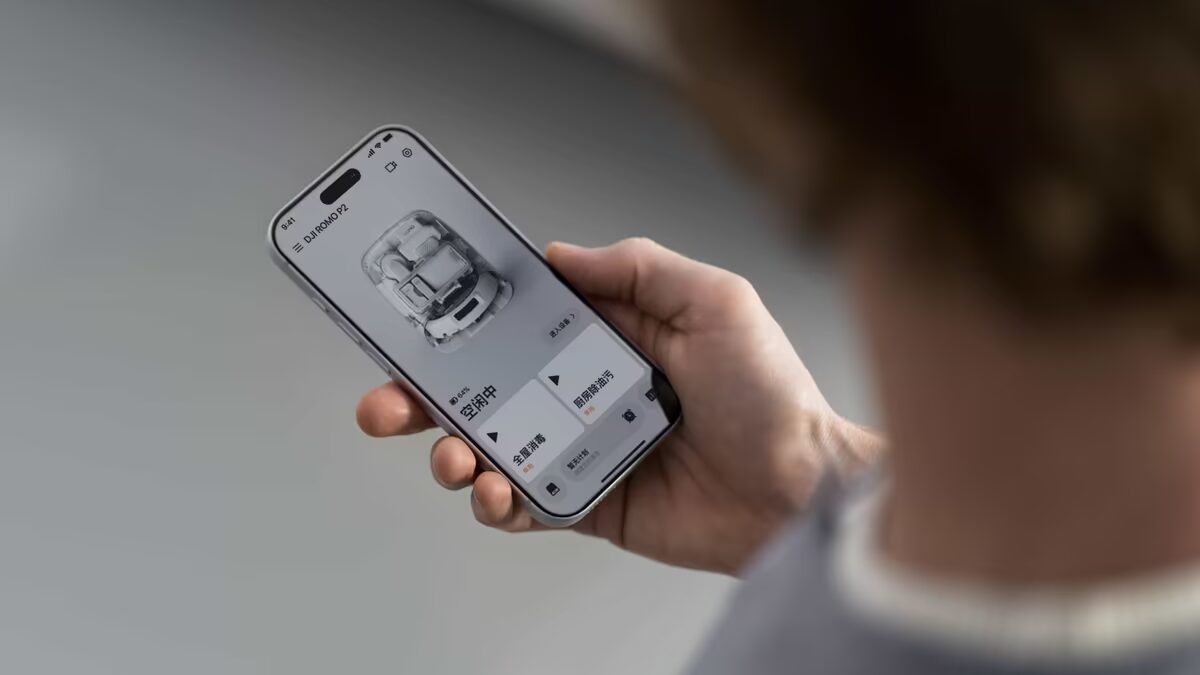 Человек с смартфоном управляет роботом-пылесосом DJI Romo 2