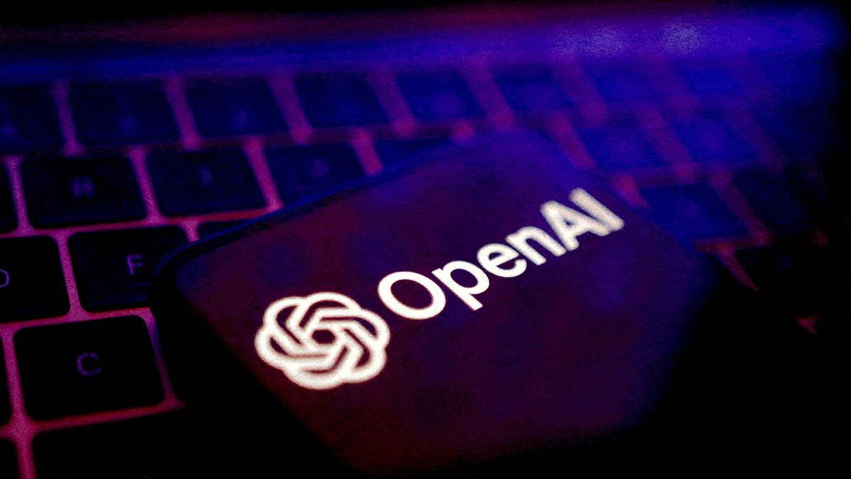 Логотип OpenAI на смартфоне на клавиатуре ноутбука