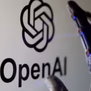 Рука в руке с роботизированными пальцами возле логотипа OpenAI