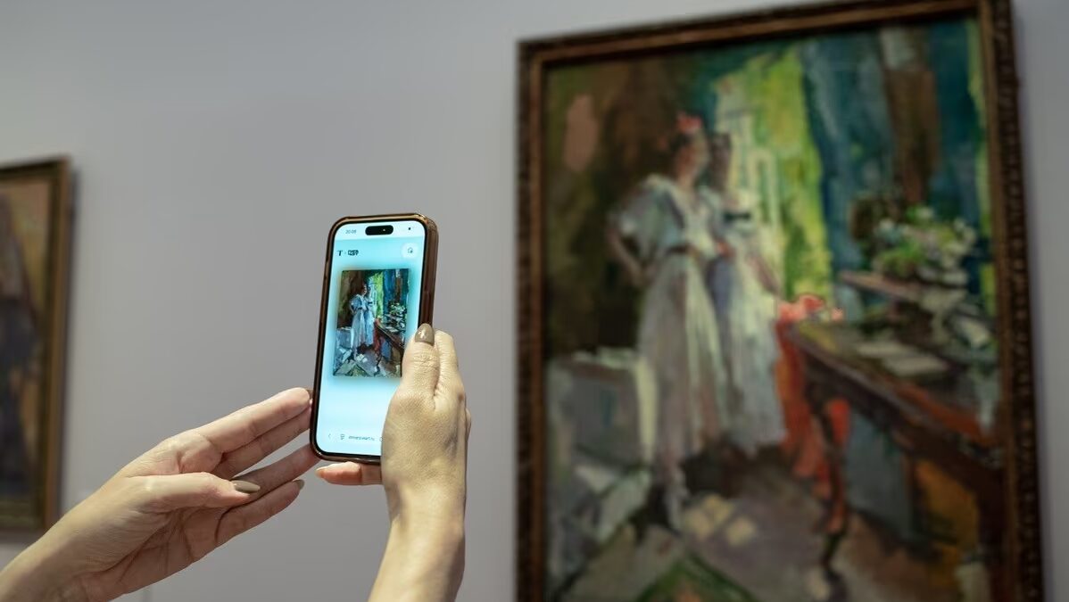 Человек фотографирует картину с помощью iPhone в Третьяковской галерее