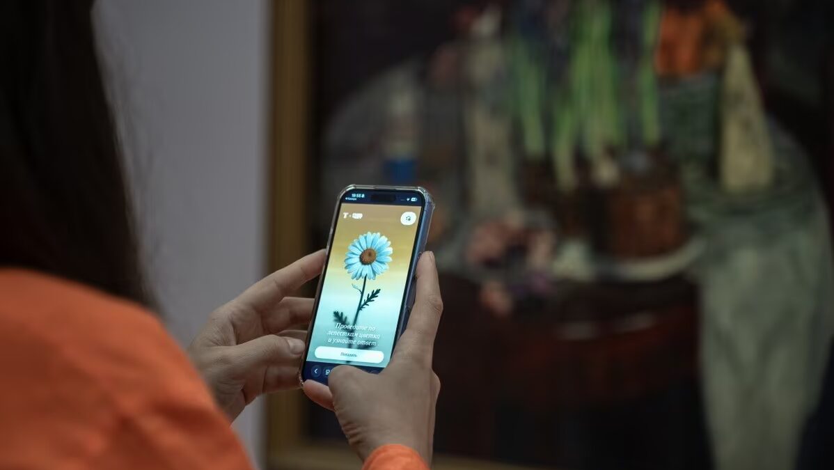 Человек держит смартфон со скринами GigaChat внутри Третьяковки