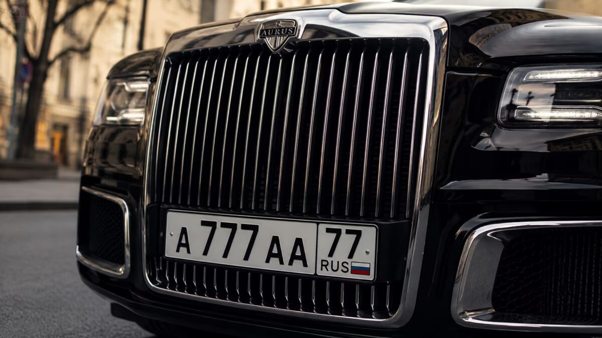 Крупный фасад автомобиля Aurus с решёткой радиатора и номером А777А 77 в центре