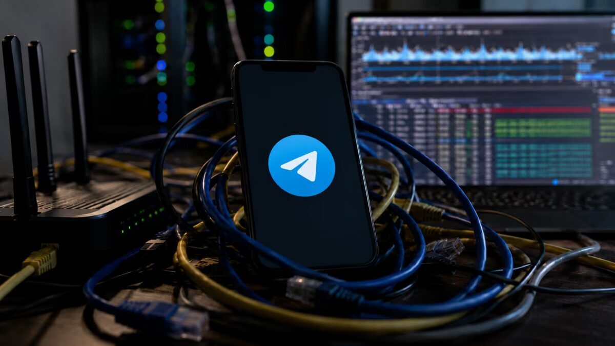 Модель смартфона с логотипом Telegram подключена к кабелям и сетевым устройствам