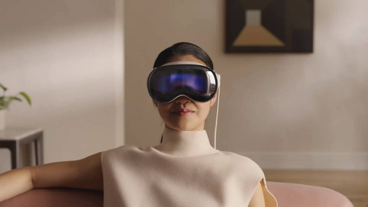 Женщина с очками виртуальной реальности Apple Vision Pro сидит на диване