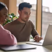 Двое людей работают за ноутбуком Apple MacBook