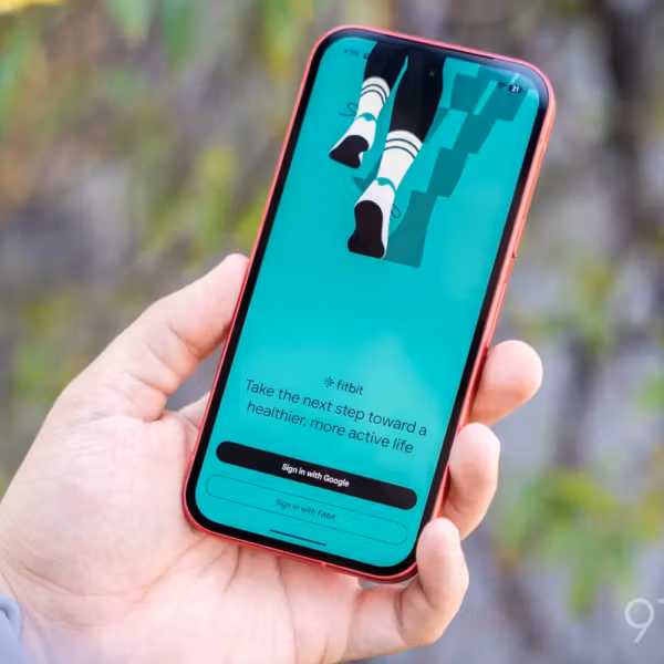 Мужчина держащий смартфон с приложением Fitbit и Google Health