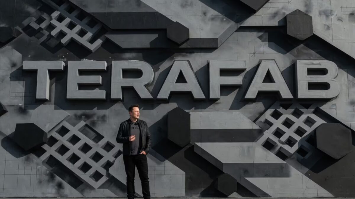 Человек стоит у стены с надписями Tesla и Terafab