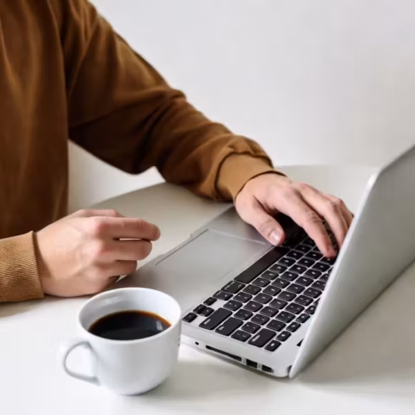 человек работает на ноутбуке с чашкой кофе