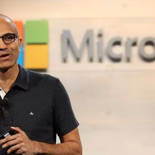 Мужчина с гнутым жестом и в черной рубашке у логотипа Microsoft