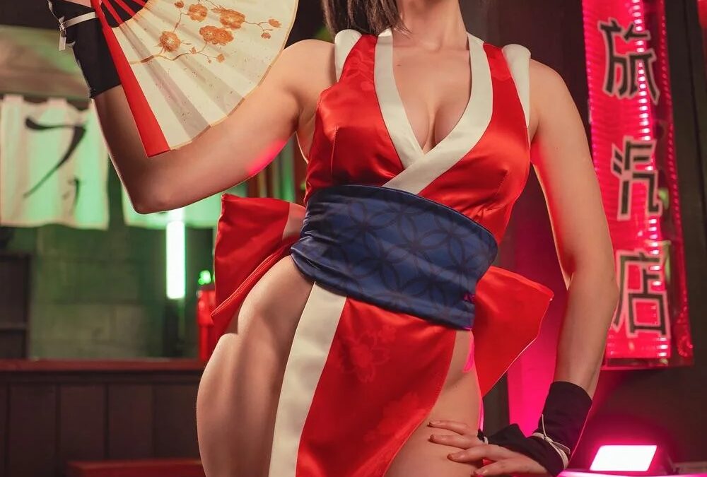 Модель в косплее Май Ширануи из Fatal Fury с веером ярко красное платье