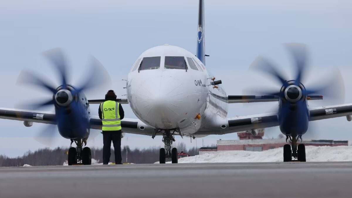 Самолет Ил-114-300 на взлётной полосе с человеком рядом