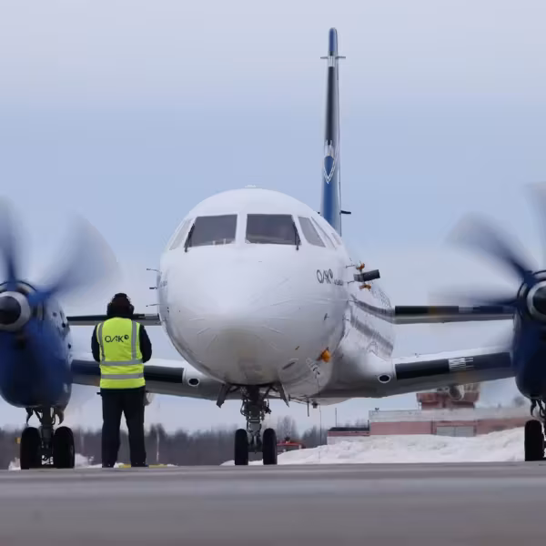 Самолет Ил-114-300 на взлётной полосе с человеком в жилетке