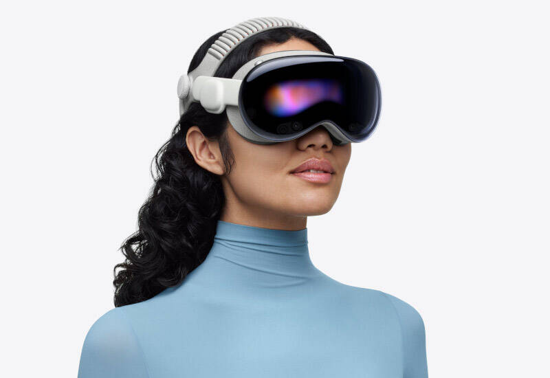 Женщина в голубой одежде с VR очками Apple Vision Pro