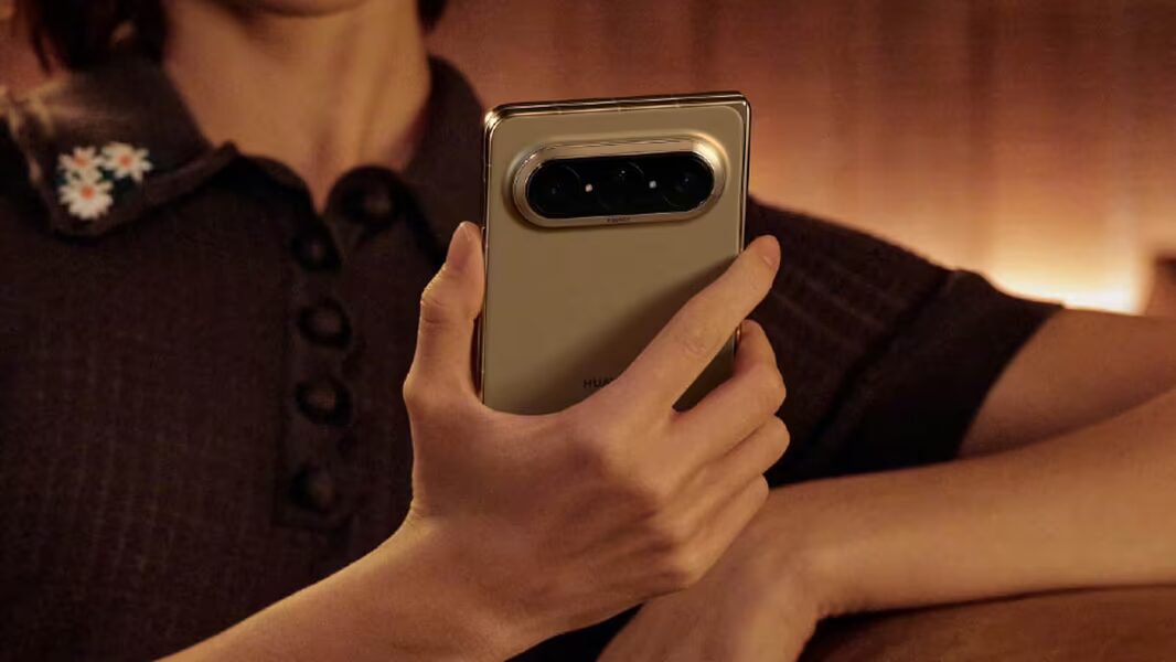 Человек держит Huawei Pura X Max в руке в темной комнате