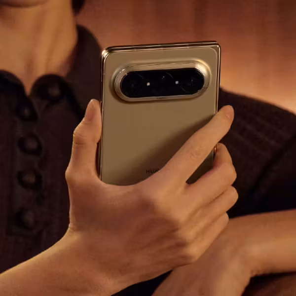 Человек держит Huawei Pura X Max в руке в темной комнате