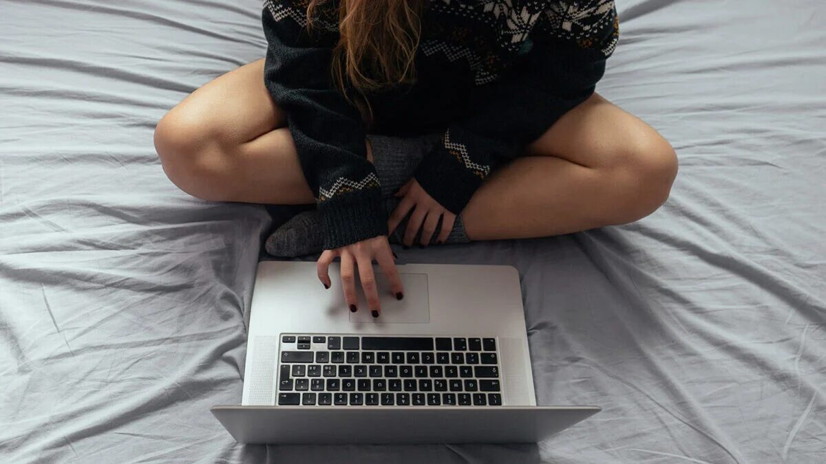 Человек сидит на кровати с ноутбуком Евросоюз VPN