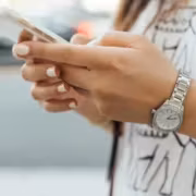 Женщина в серебряных часах пользуется смартфоном API Tenor