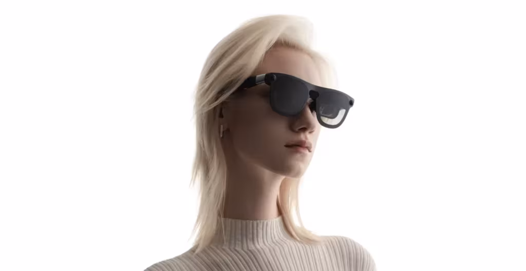 Блондинка в черных очках Xreal Aura и светлая кофточка