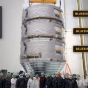 Группа людей в защитной одежде перед крупным спутником BlueBird 8, 9, 10 Astra SpaceMobile