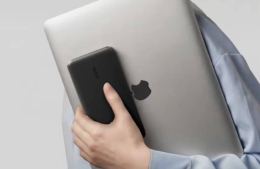Человек держит powerbank Belkin UltraCharge Pro 25K и MacBook