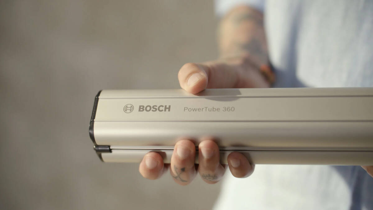Рука держит устройство Bosch PowerTube 360 электровелосипеда