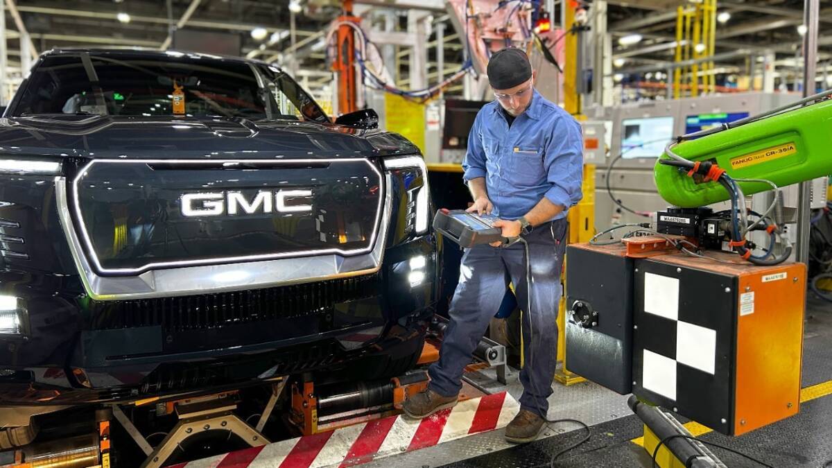Работник на заводе GM с роботом для сборки автомобиля GM