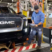 Работник на заводе GM с роботом для сборки автомобиля GM