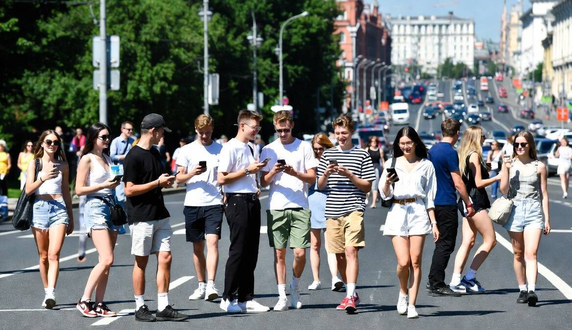 Группа молодых людей на улице использует смартфоны для общения