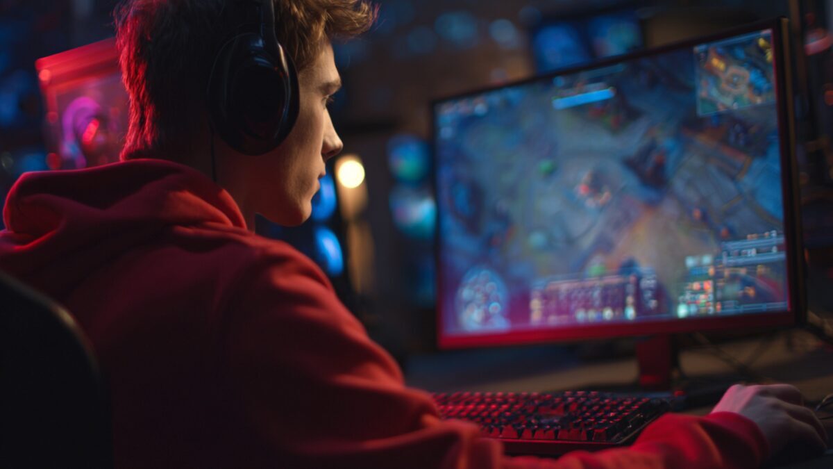 молодой человек с наушниками за компьютером играющий в игру на мониторe Steam