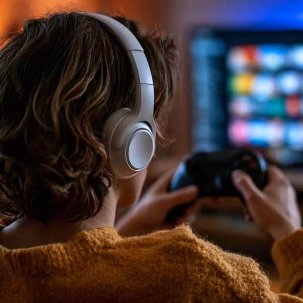 женщина в наушниках играет на приставке PlayStation со смартфоном
