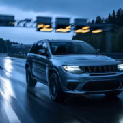 Черная внедорожник Jeep Grand Cherokee на мокрой трассе в дождь