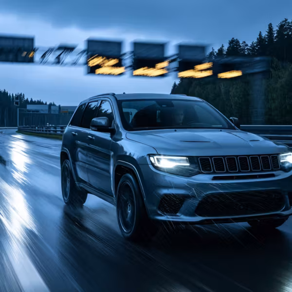 Черная внедорожник Jeep Grand Cherokee на мокрой трассе в дождь