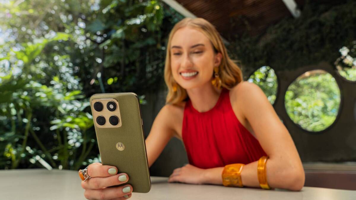 Женщина в красном платье держит телефон Motorola Edge 2026 на открытом воздухе