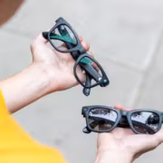 Мужчина держит две пары очков с объективами Ray-Ban