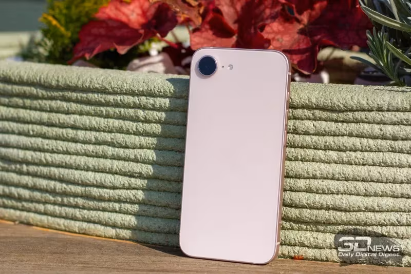 белый iPhone 17e стоит на деревянной поверхности у растения