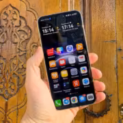 Hand holding HUAWEI Mate 80 Pro смартфон у деревянной дверцы