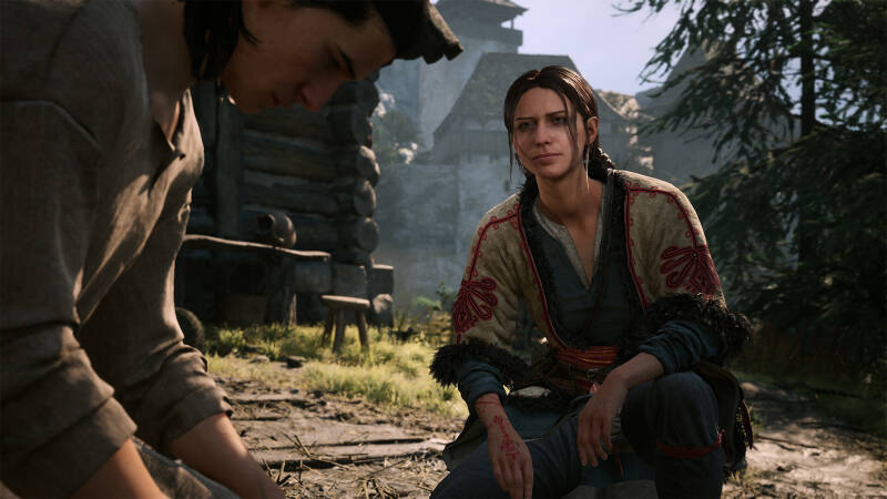 Женщина в традиционной одежде с драконами, сидящая на земле в лесу