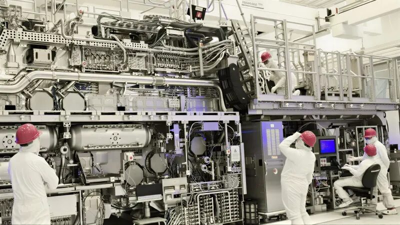 люди в белых комбинезонах и красных касках у сверхмощного полупроводникового оборудования