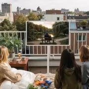 Три человека смотрят LG StanbyME 2 Max на балконе